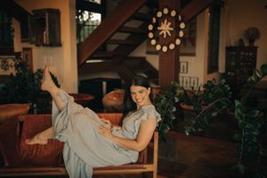 Candid indoor portrait relaxing in casual pose on chair with warm lighting.