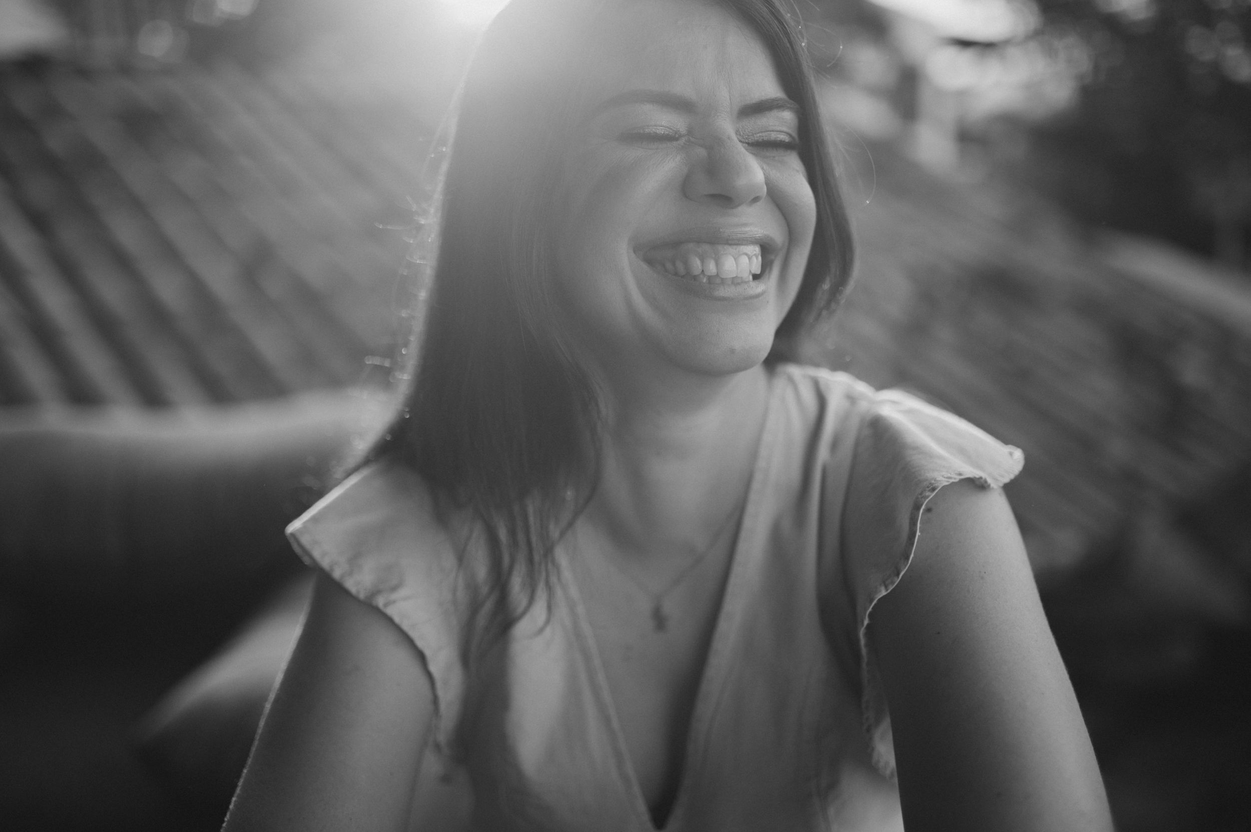 A candid black and white portrait capturing genuine laughter in natural sunlight.