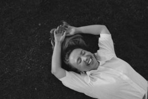 Black and white image of person lying on grass with carefree expression.