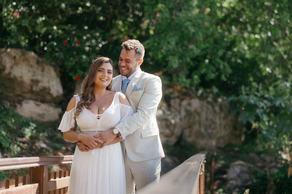 A bride and groom share a romantic moment on a wooden bridge surrounded by lush greenery on their wedding day.