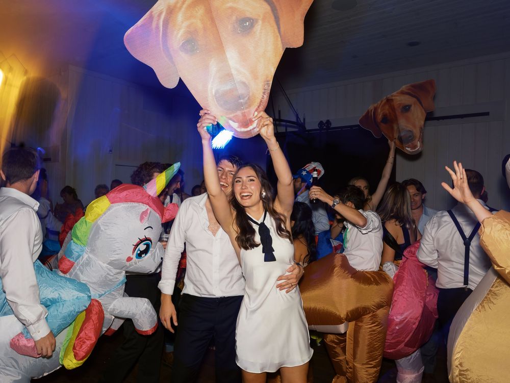 Lively party scene with guests in colorful unicorn and dog costumes dancing under blue lights at a festive celebration.