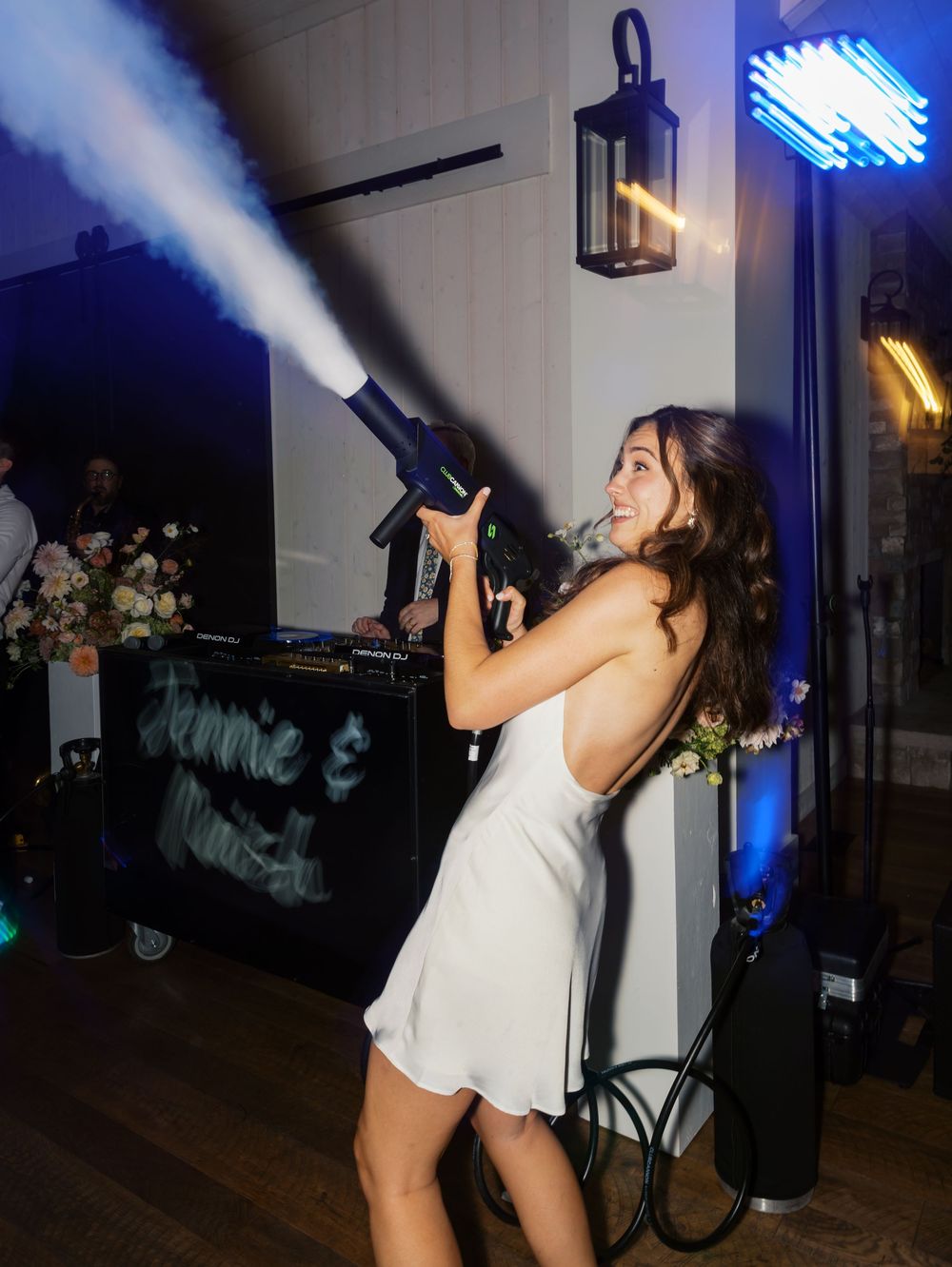 Bride in white mini dress operating a CO2 cannon at her wedding reception party.