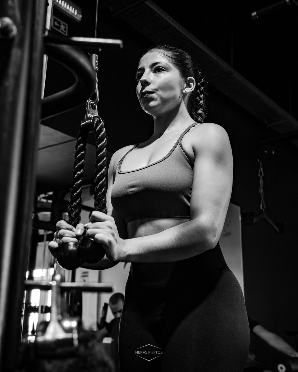 Woman in sports bra doing cable tricep pushdowns at gym in black and white photo.