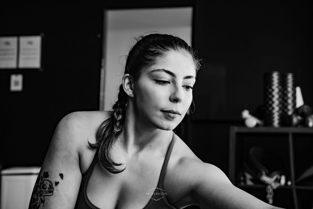 Black and white portrait of tattooed woman in athletic wear at gym.