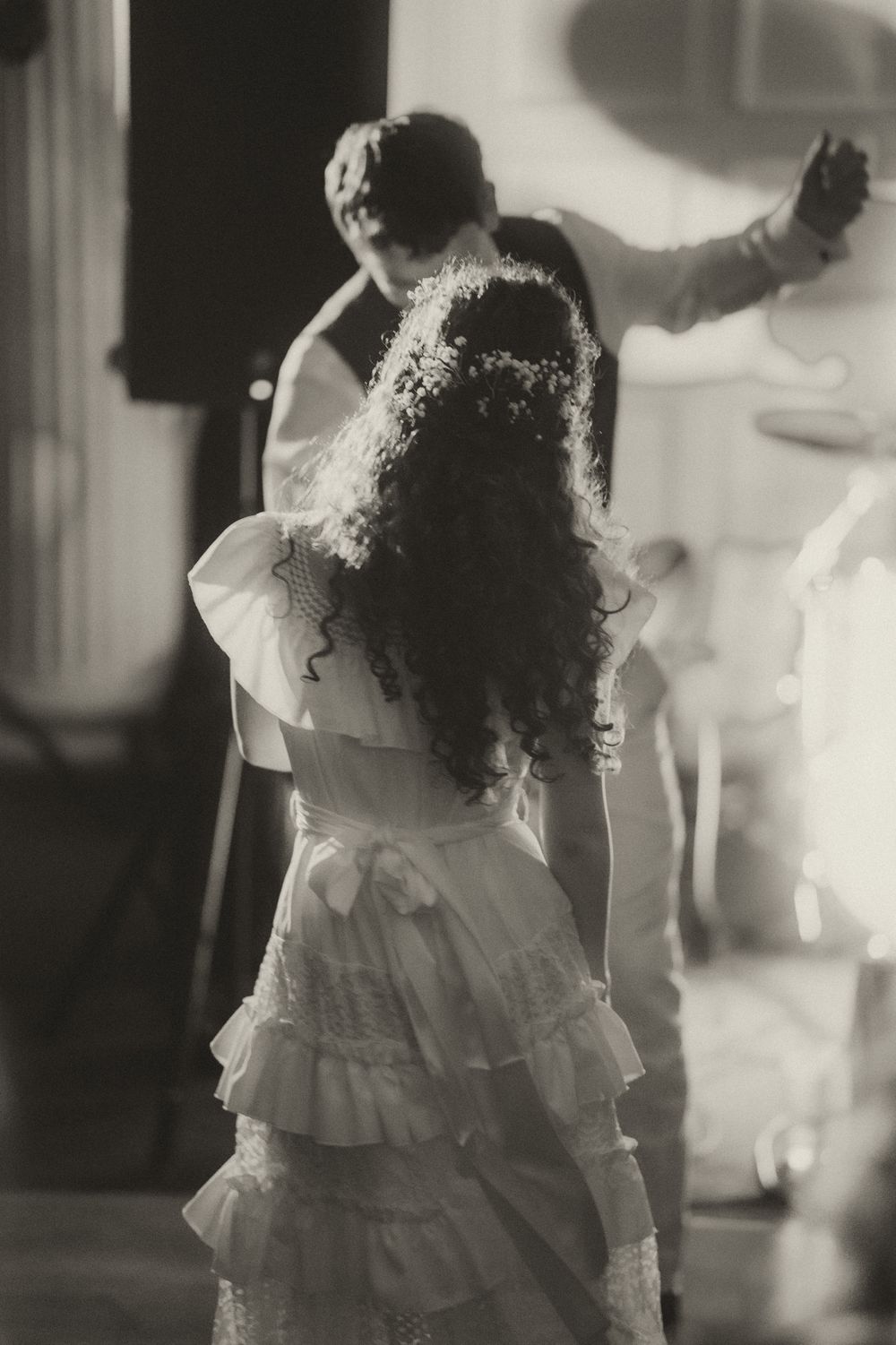 Black and white photo of a bride in ruffled dress dancing with groom at wedding reception.
