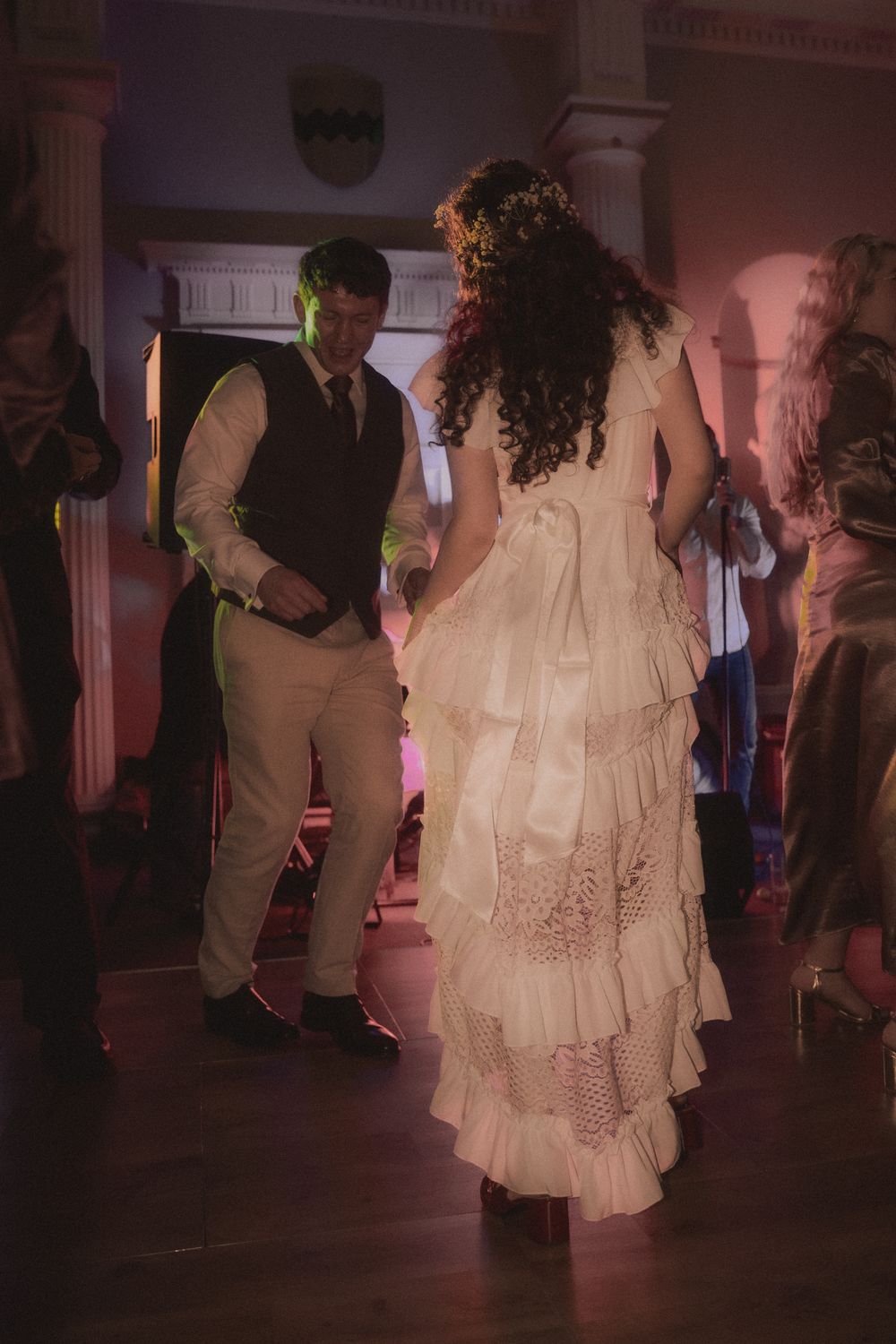 Couple sharing a first dance at a wedding reception in an elegant venue with warm lighting.