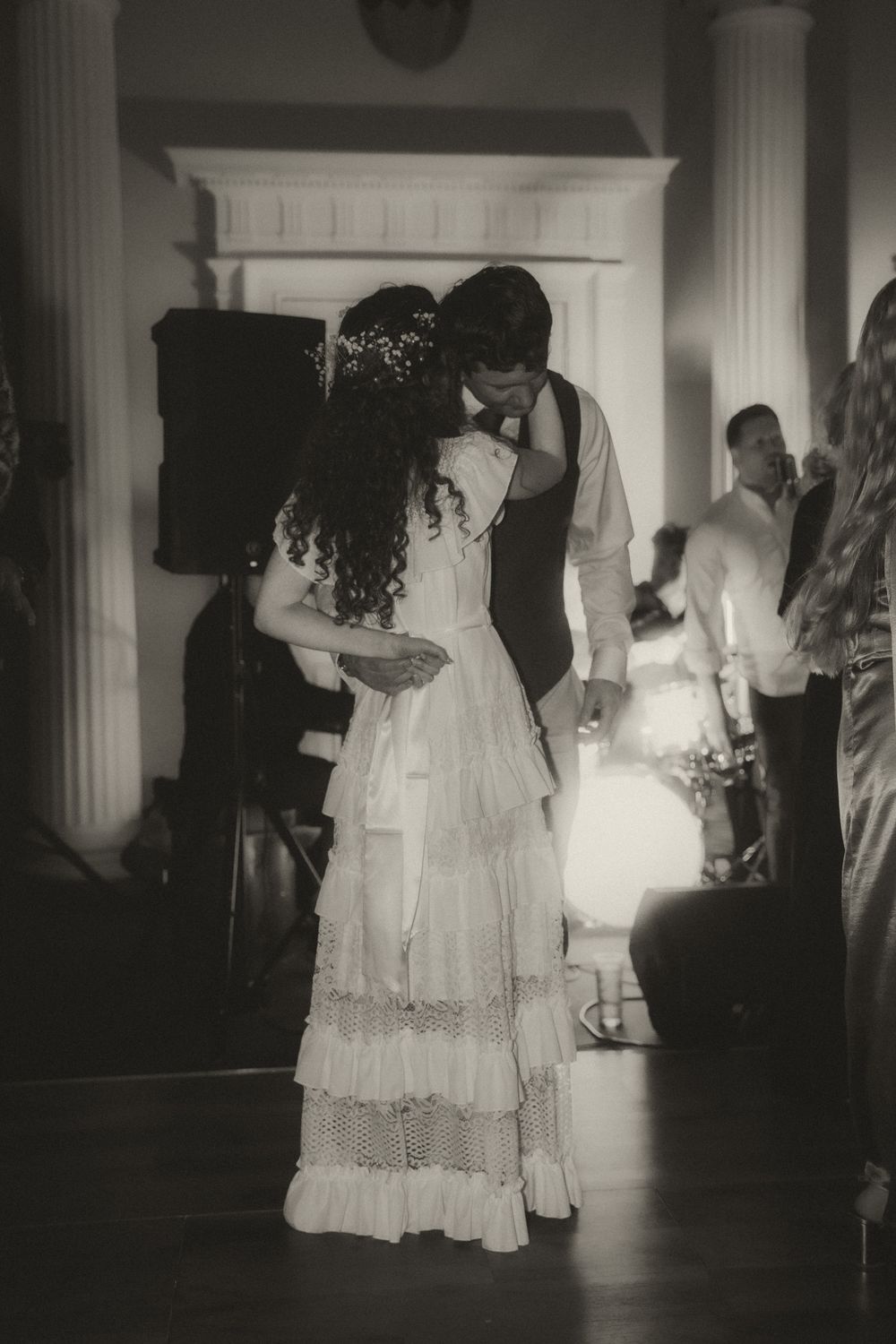 Black and white photo of a bride and groom sharing their first dance at a wedding reception.