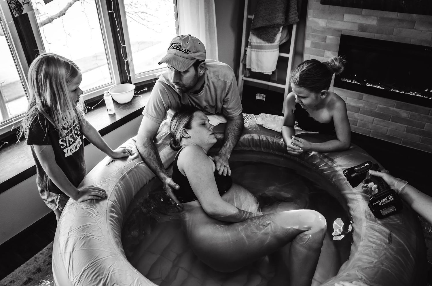 Family gathering around an inflatable pool during an intimate home birth setting.