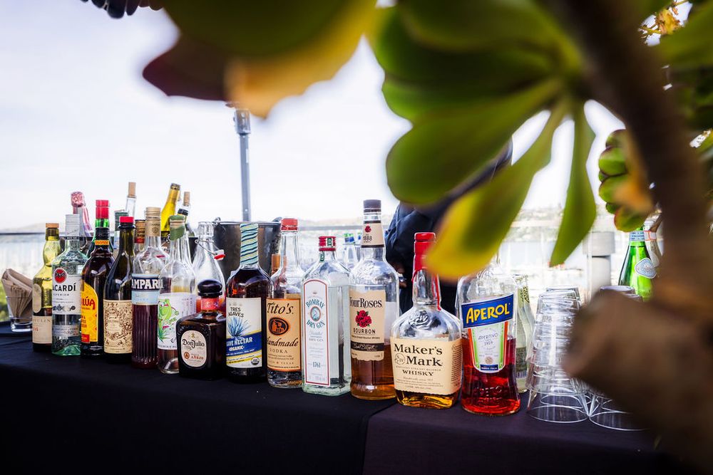 Assorted liquor bottles lined up on a bar table at an outdoor event.
