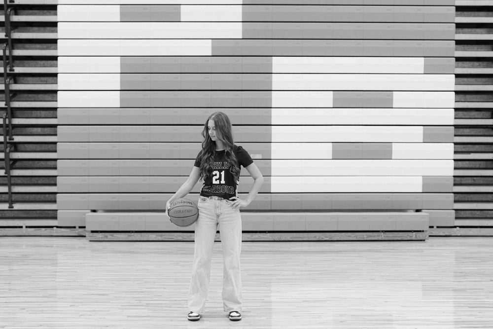 Black and white photo of female athlete in Philip Barbour jersey number 21 holding basketball in gym.