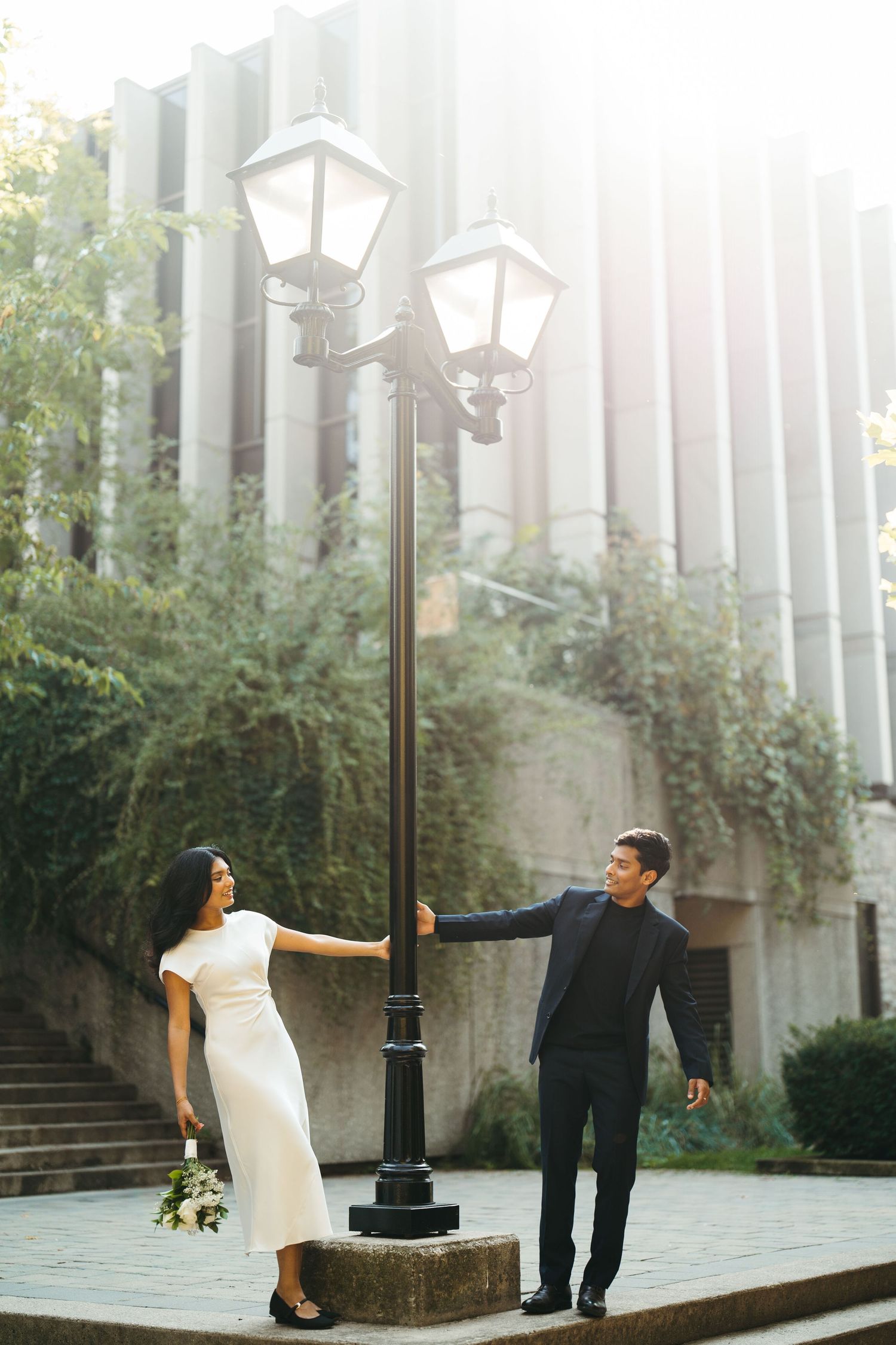 Couple in urban hallway at night, woman bending forward with flowers, man leaning against wall in moody lighting in Toronto