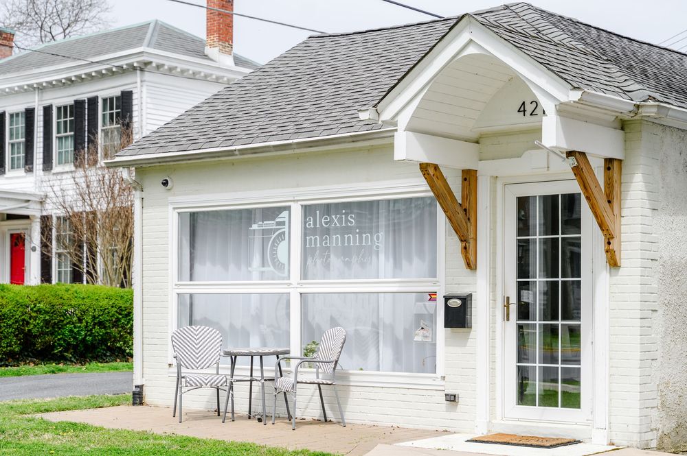 White brick cottage office of Alexis Manning with patio seating, decorative brackets, and address number 42 on the entrance.