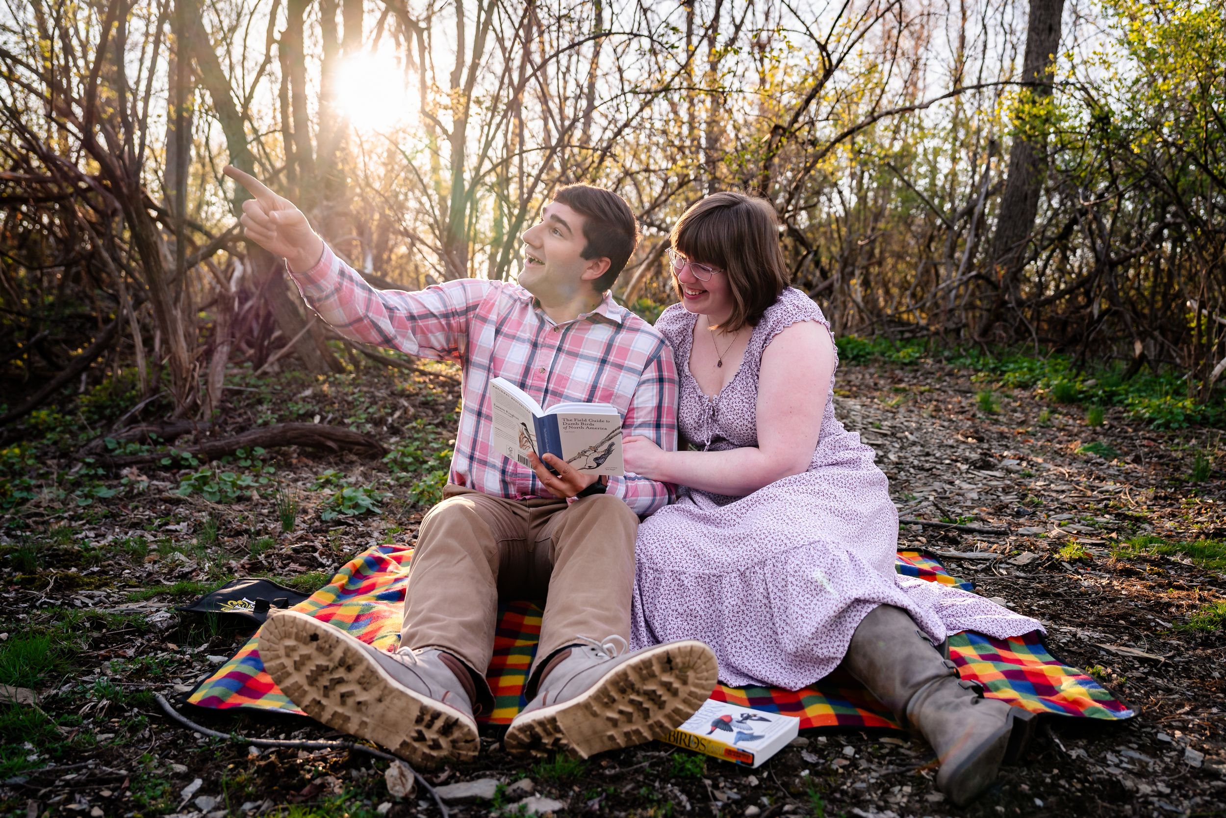 Couple sitting on a blanket in the woods reading books together at sunset.