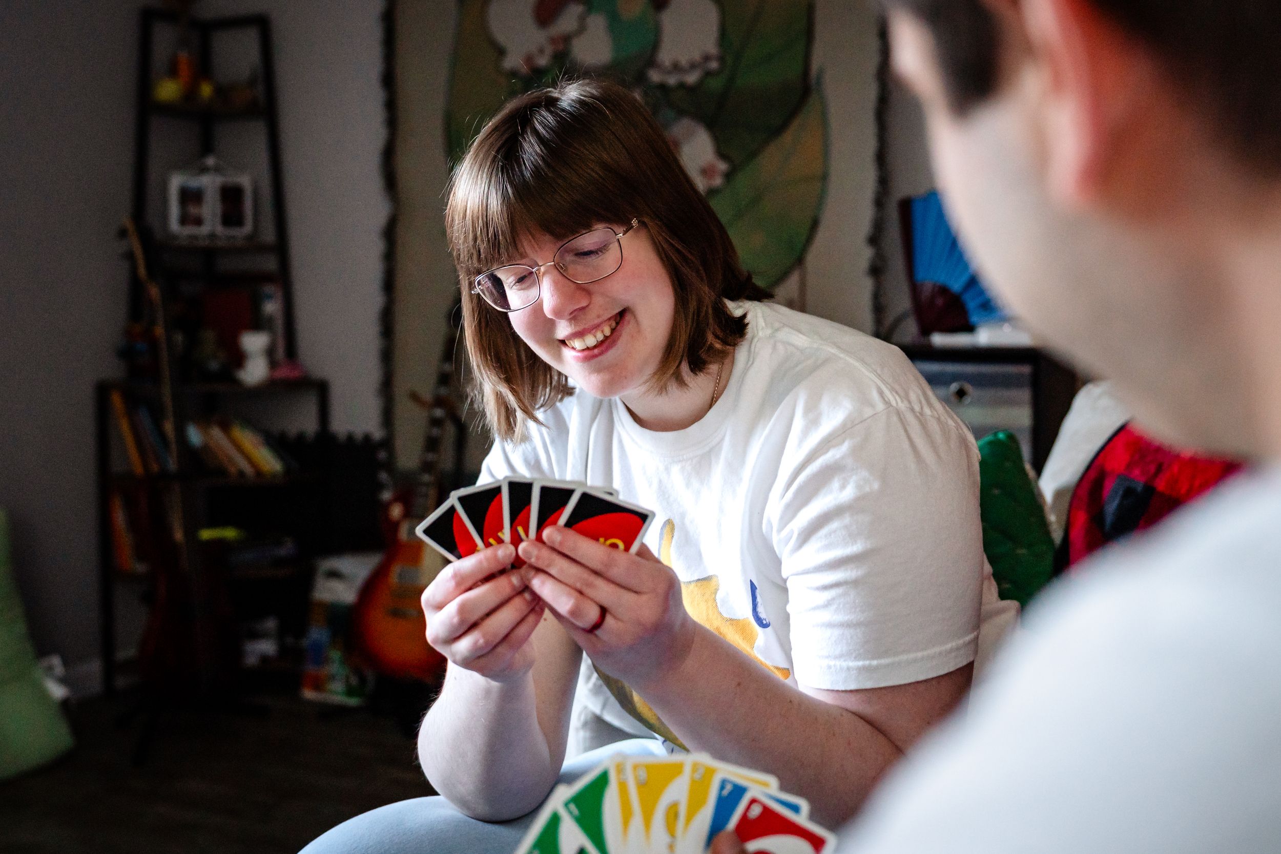 Young woman smiling while holding Uno cards during a fun indoor card game session.