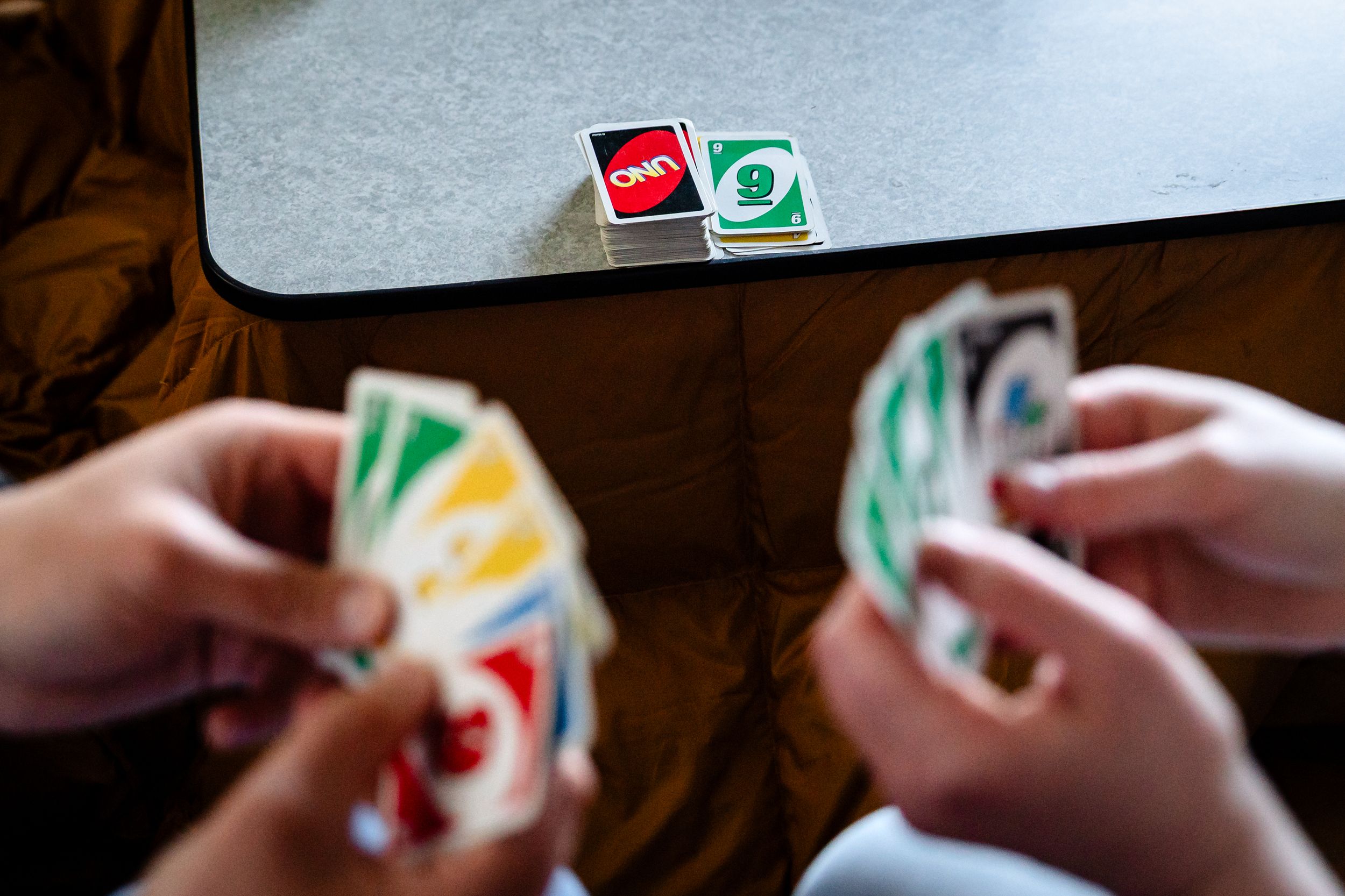 Overhead view of two people holding Uno cards during a card game.