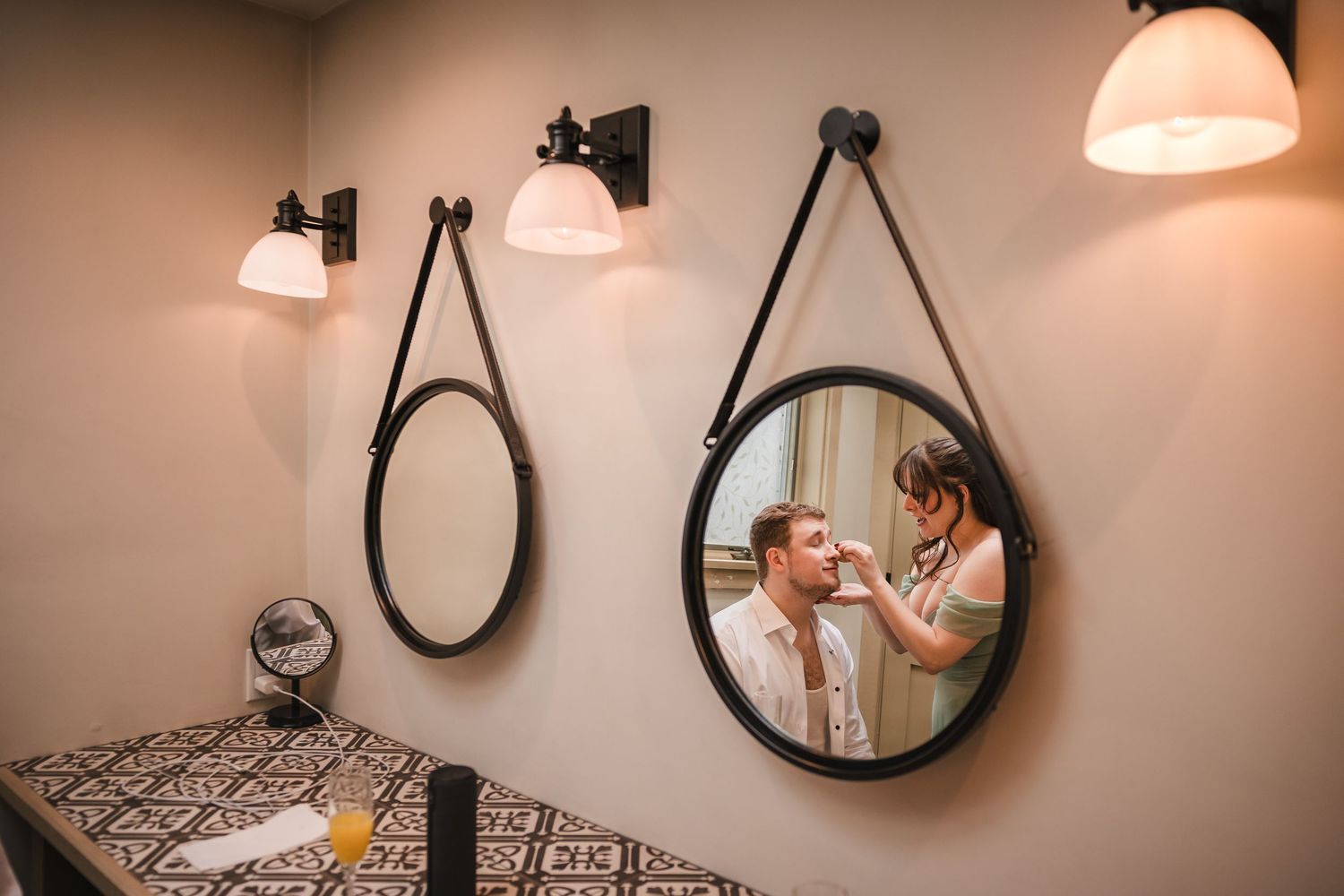 Groom getting ready reflected in mirror with maid of honor at Briar Barn Inn wedding in Massachusetts