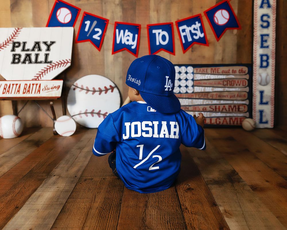 Small baseball jersey and sports decor with Way to Play Ball banner on wooden backdrop taken by local photographer in Fresno,ca