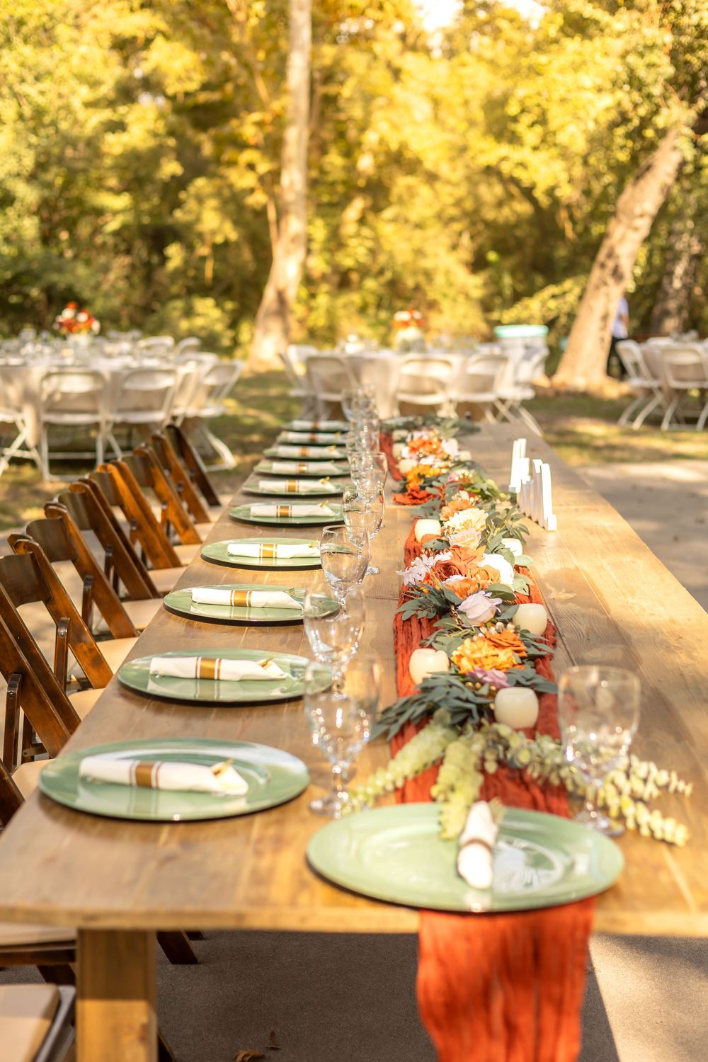 Rustic outdoor wedding table setting with wooden chairs and mint green plates decorated with orange floral centerpieces taken in fresno,ca.