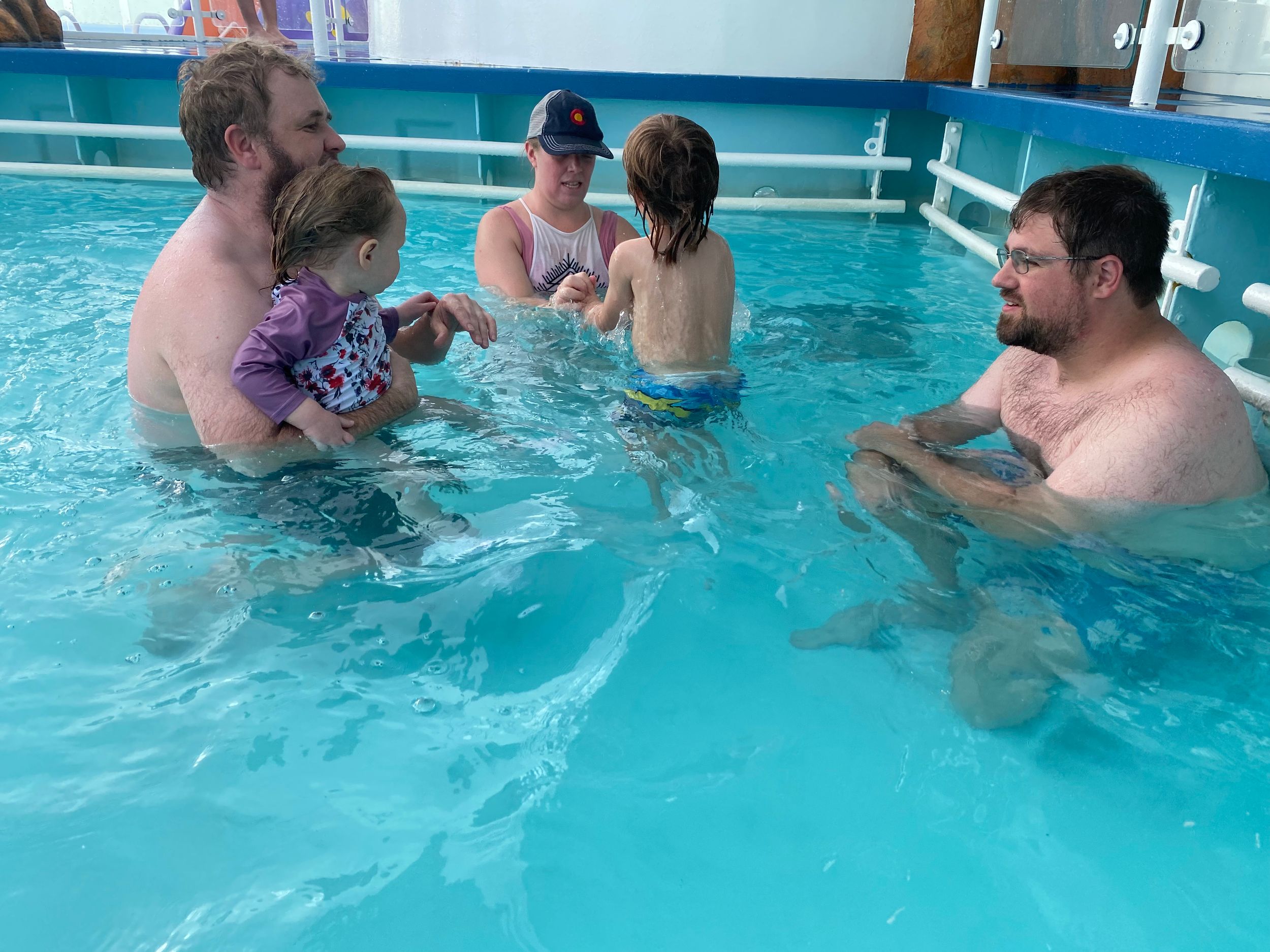 Adults and children enjoying an indoor swimming pool during a family swim lesson session.