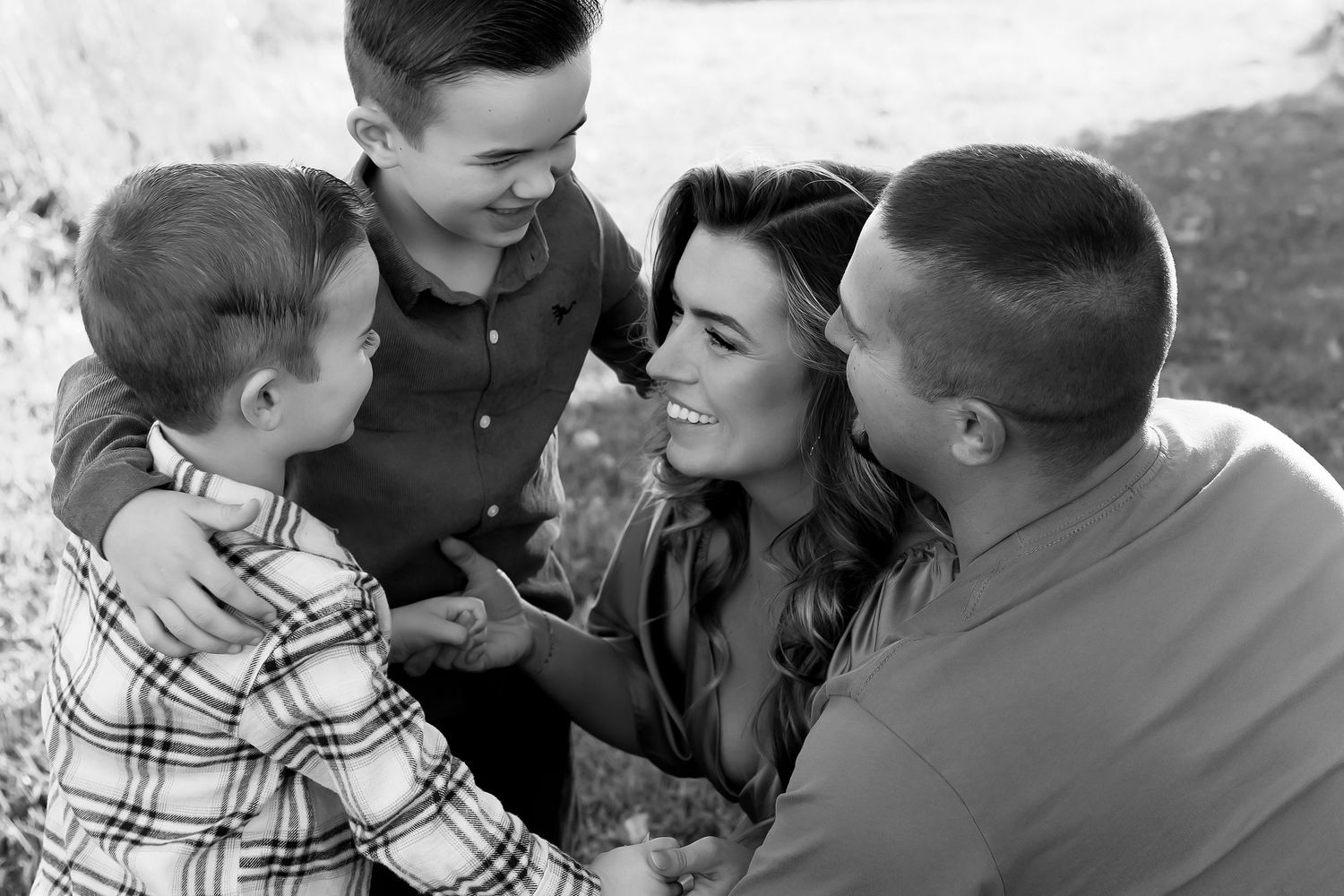 A joyful family sharing a tender moment together outdoors in black and white photography.