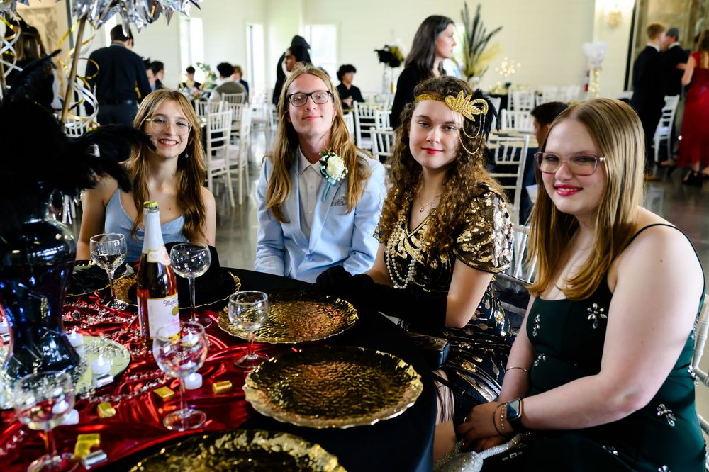 A group enjoying a holiday dinner gathering at a decorated table with festive glassware and plates.
