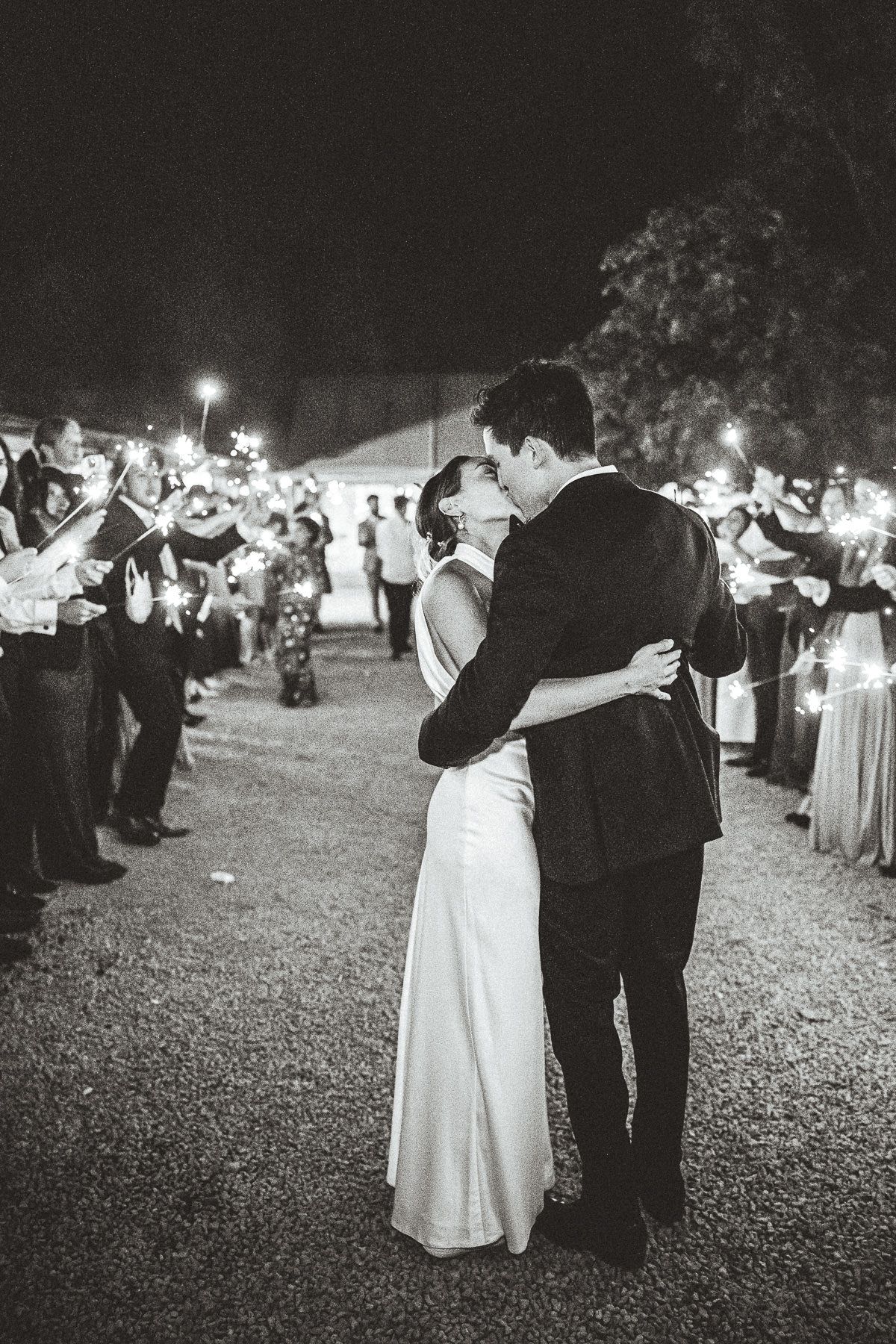 Couple shares their first dance on a black and white checkered floor under dramatic purple-lit Gothic cathedral arches.
