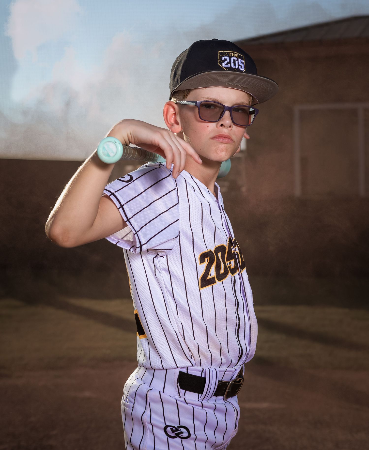 Creative youth baseball photography in Lincoln, Alabama, featuring smoke effects and sunset lighting.