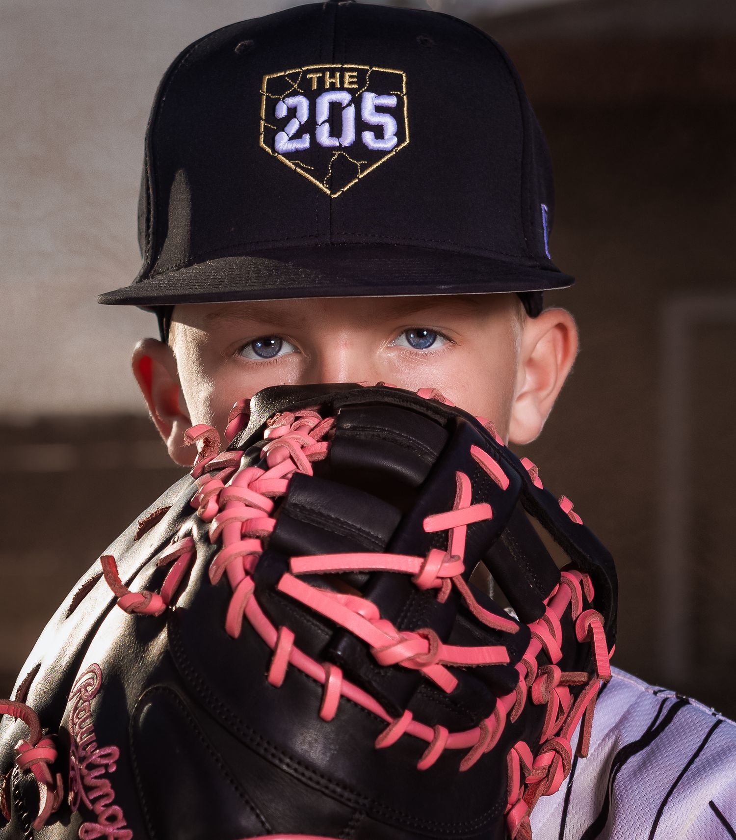 Intense close-up youth baseball portrait in Lincoln, Alabama, focusing on player's eyes behind a catcher's mitt
