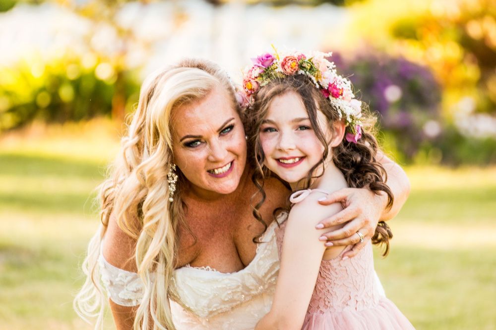 A tender outdoor moment captured with two beautifully styled figures in soft sunlit lighting with floral accents.