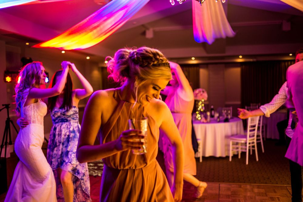 Wedding reception dance floor with colorful uplighting creates vibrant atmosphere as guests dance and celebrate.