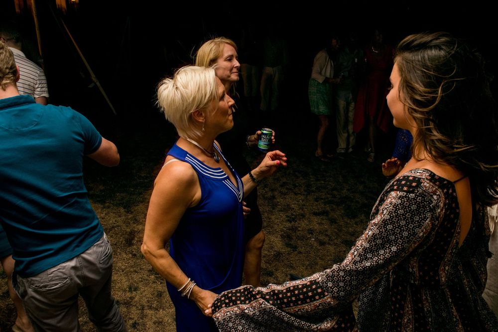Wedding guests socialize and converse at an outdoor evening reception.