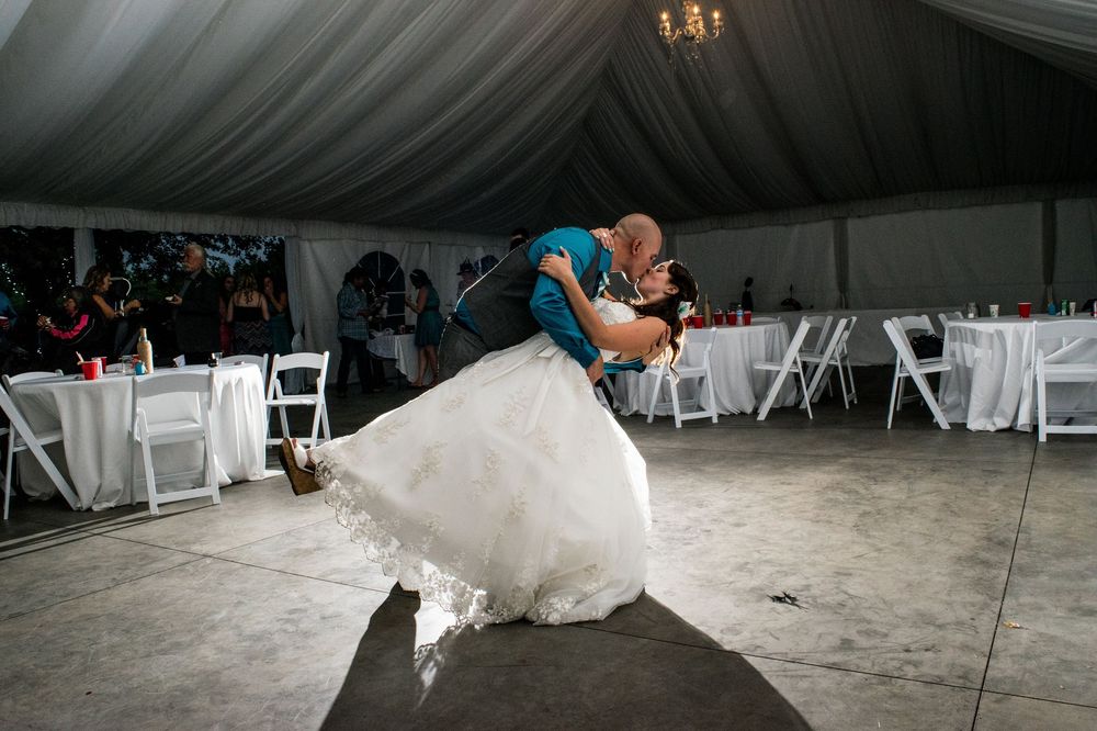 A dramatic dip during a wedding dance in a white tented reception venue.