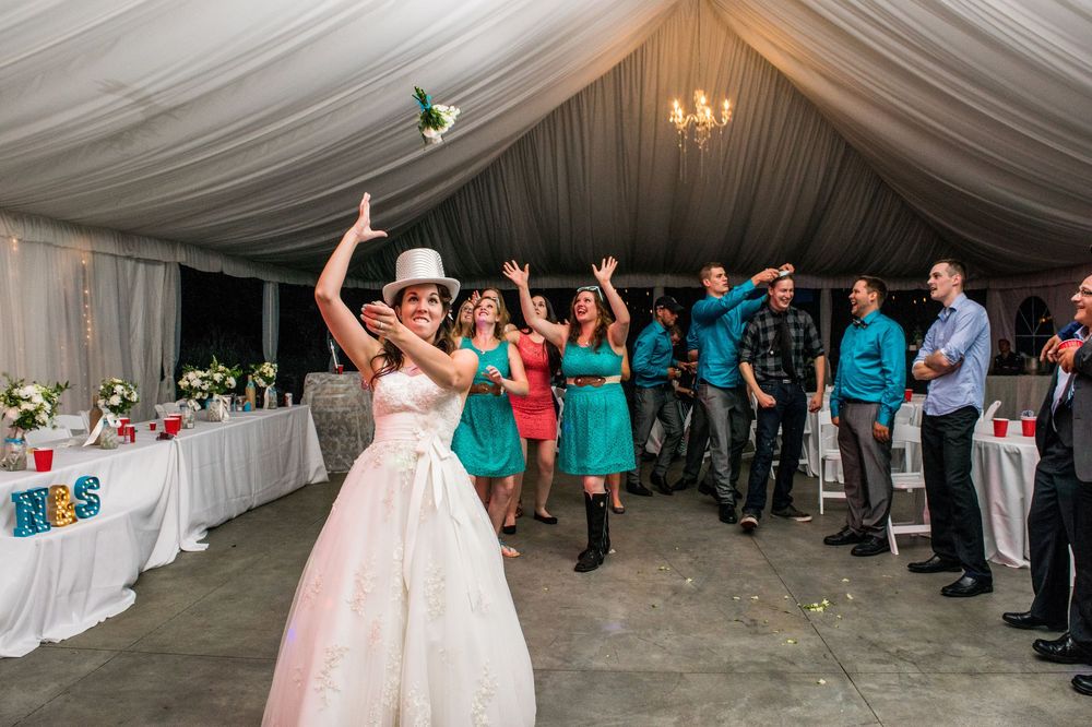 A celebration in a white draped tent venue with people dancing and raising their arms in festivities.
