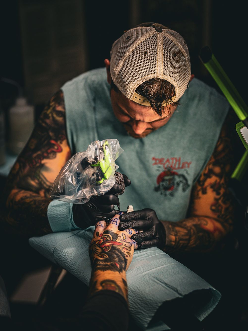 Person with sleeve tattoos examining something in dim lighting.