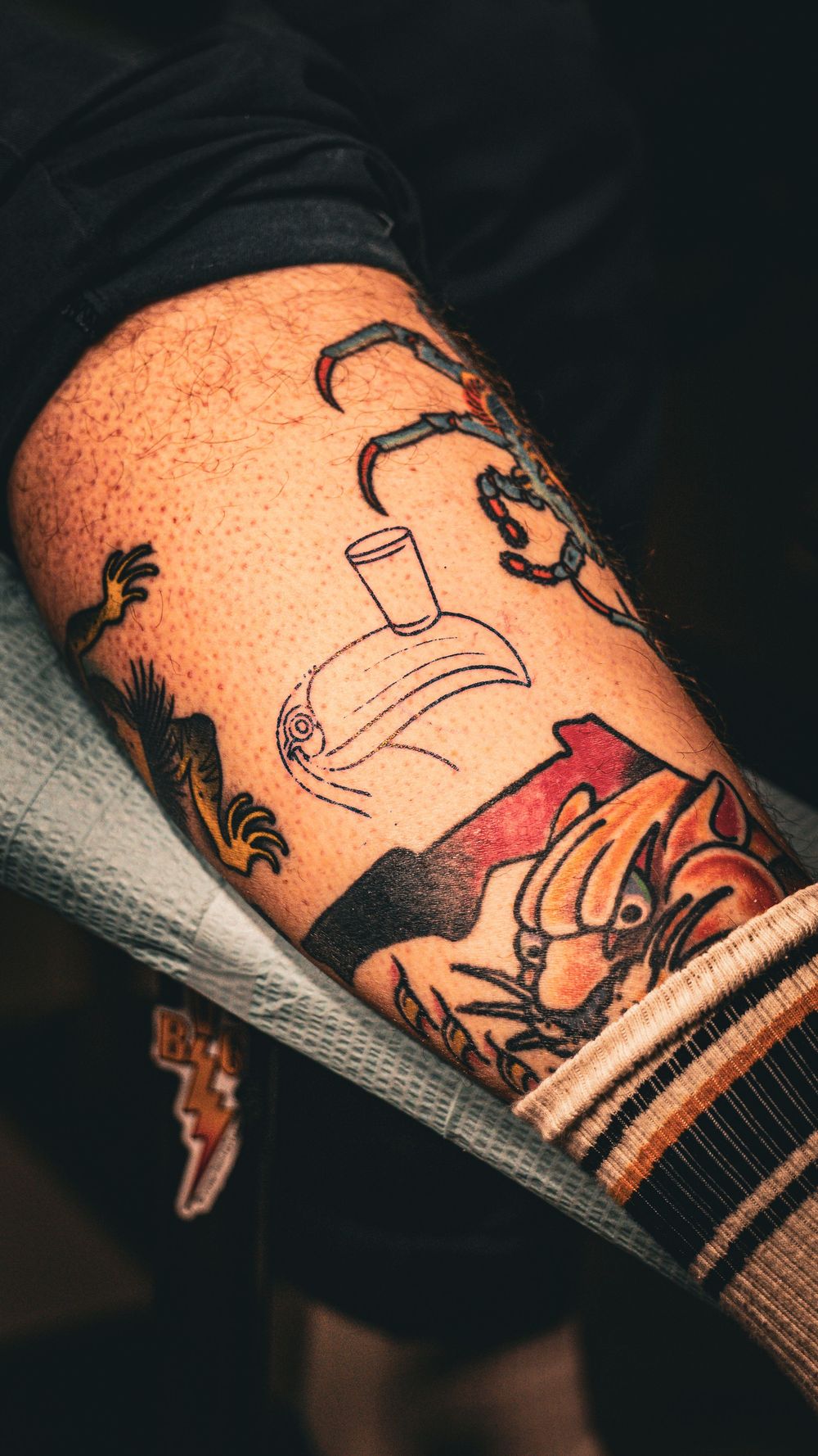 Artistic tattoo design featuring bottle and figures inked on skin.