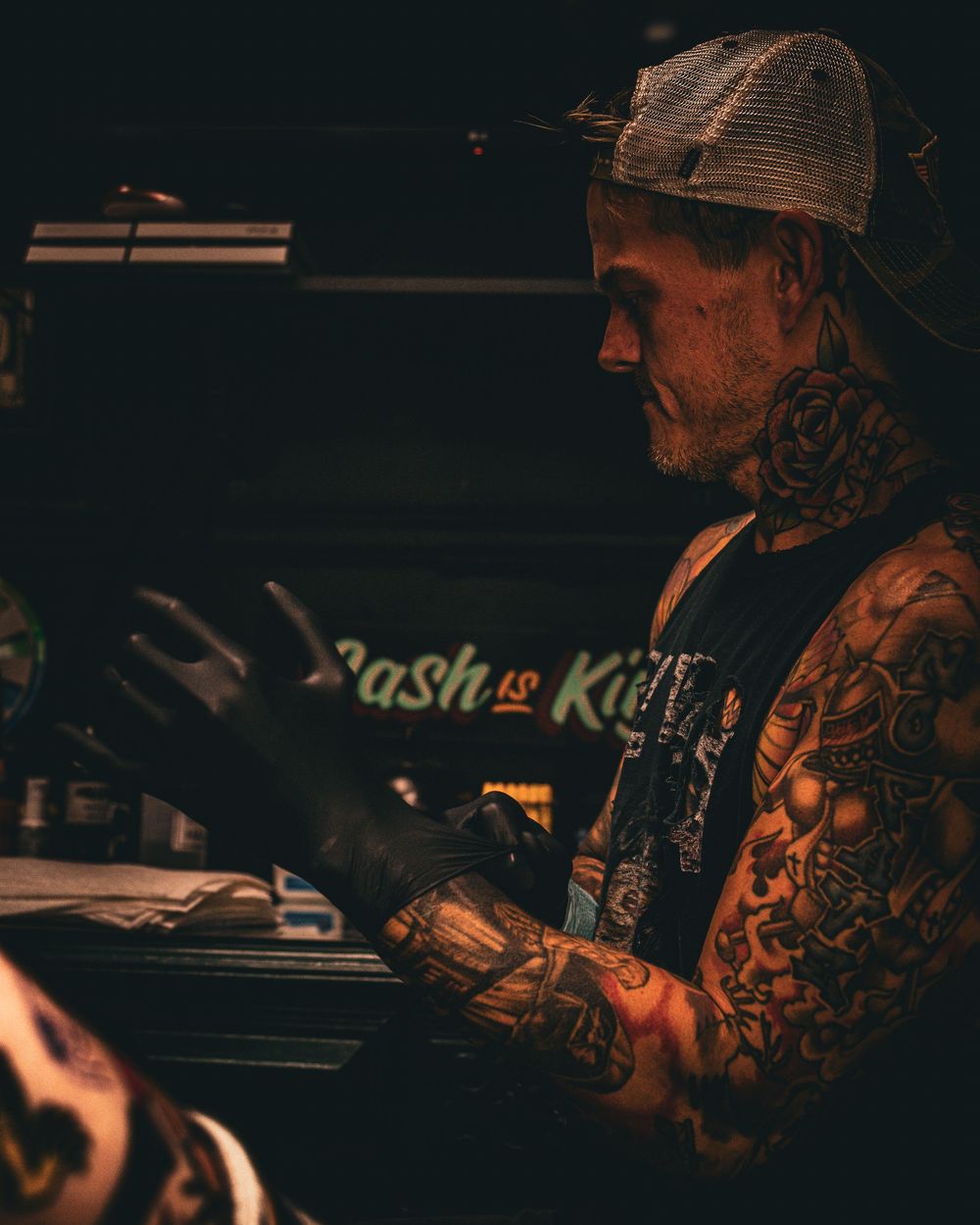 Tattoo artist at work in dimly lit studio environment.