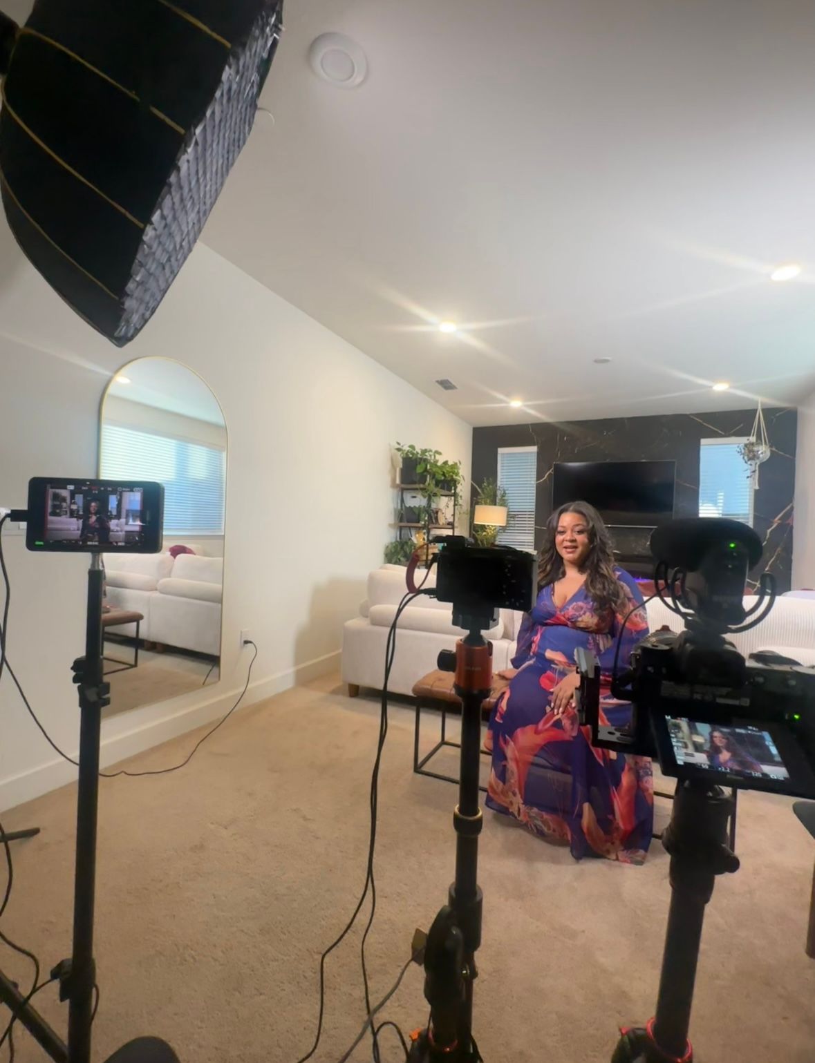 Professional video production setup in an office room with cameras, lighting equipment and backdrop against gray carpeted floor.
