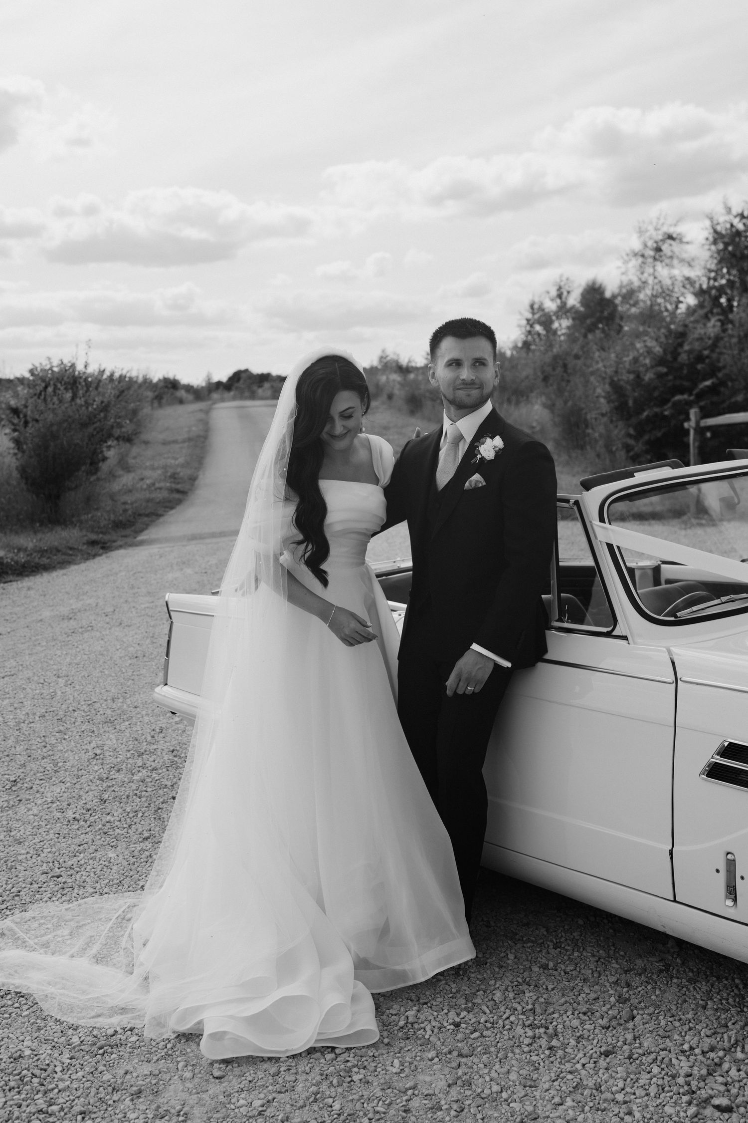 bride and groom leaning against vintage car at yardspace old gore in cirencester