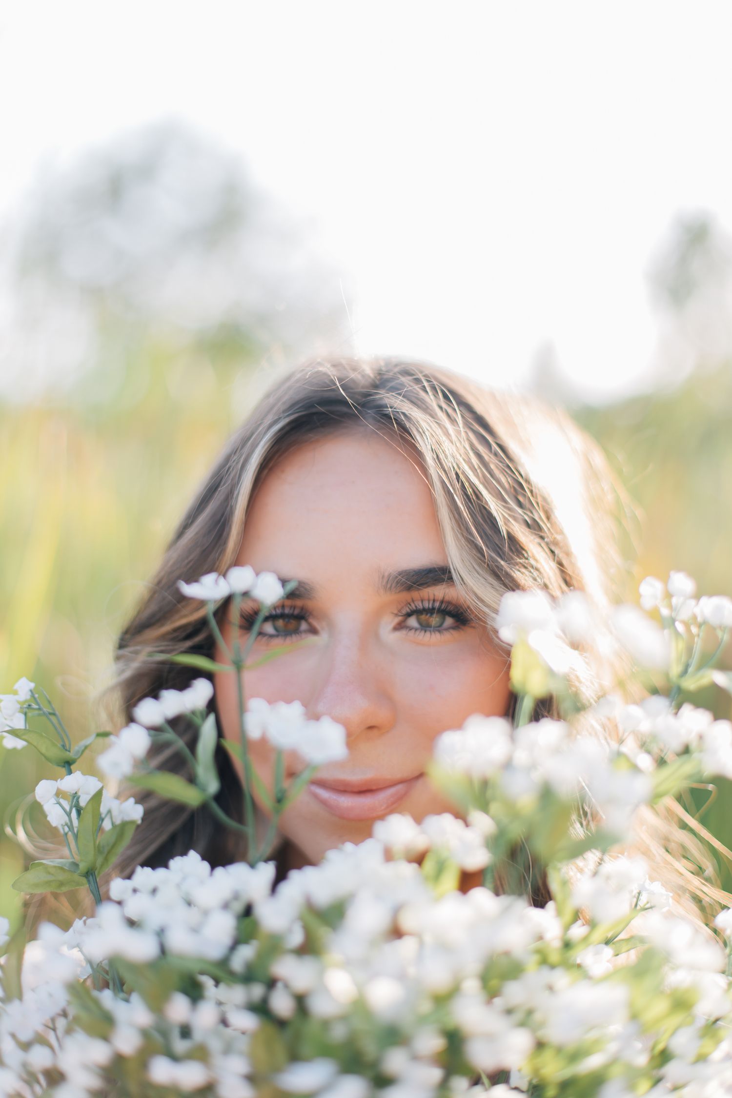 Close up portrait surrounded by white wildflowers in soft natural light.