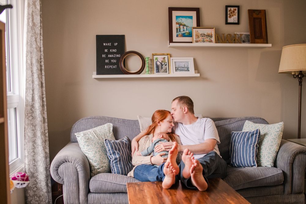 Happy couple sharing a kiss on grey sofa in cozy living room with decor.