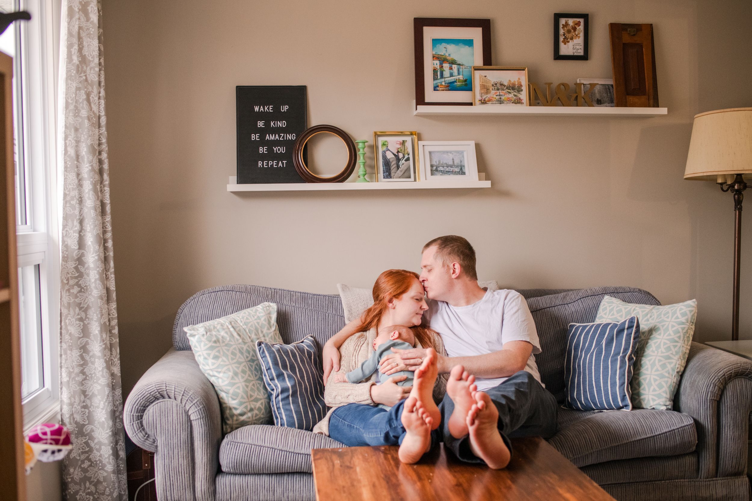 Happy couple sharing a kiss on grey sofa in cozy living room with decor.