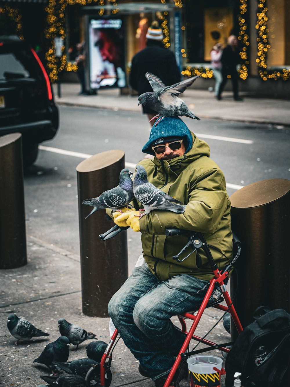 Pigeons gathering around someone on red mobility scooter on city sidewalk.
