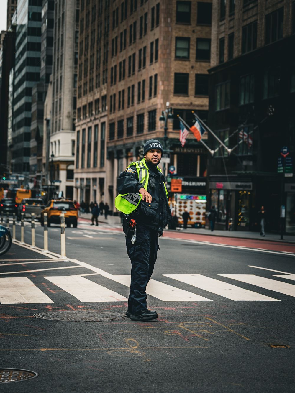 Traffic officer directing vehicles at busy downtown intersection with tall buildings.