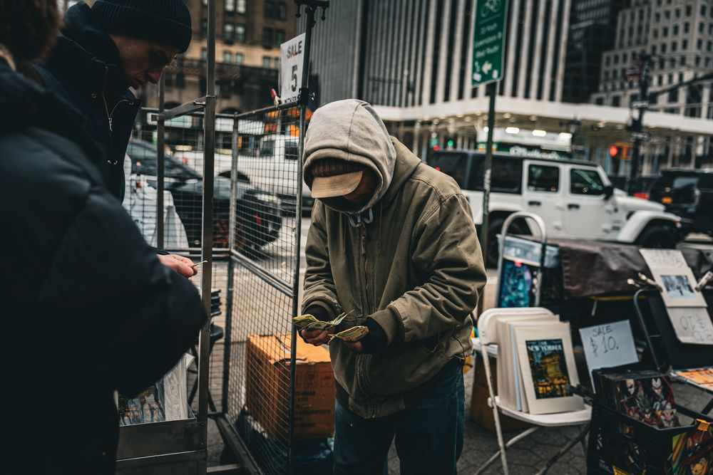 Urban street scene with food vendors and city buildings in moody lighting.