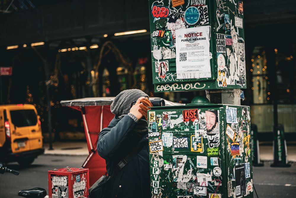 Urban wall covered in colorful posters and street art in downtown setting.