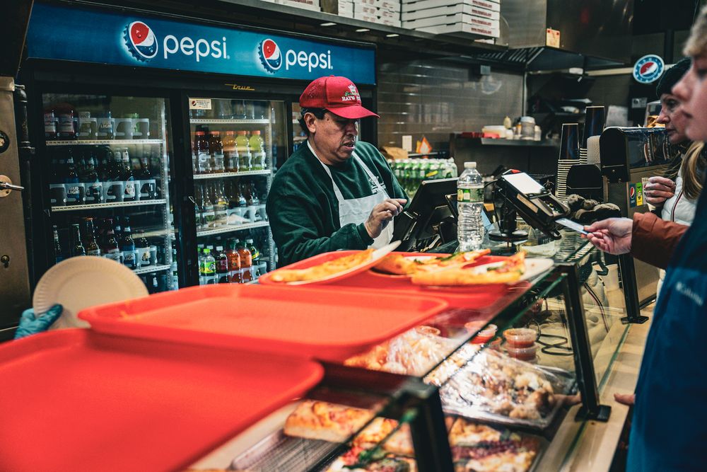 Deli counter with red awning and Pepsi signage in urban storefront.