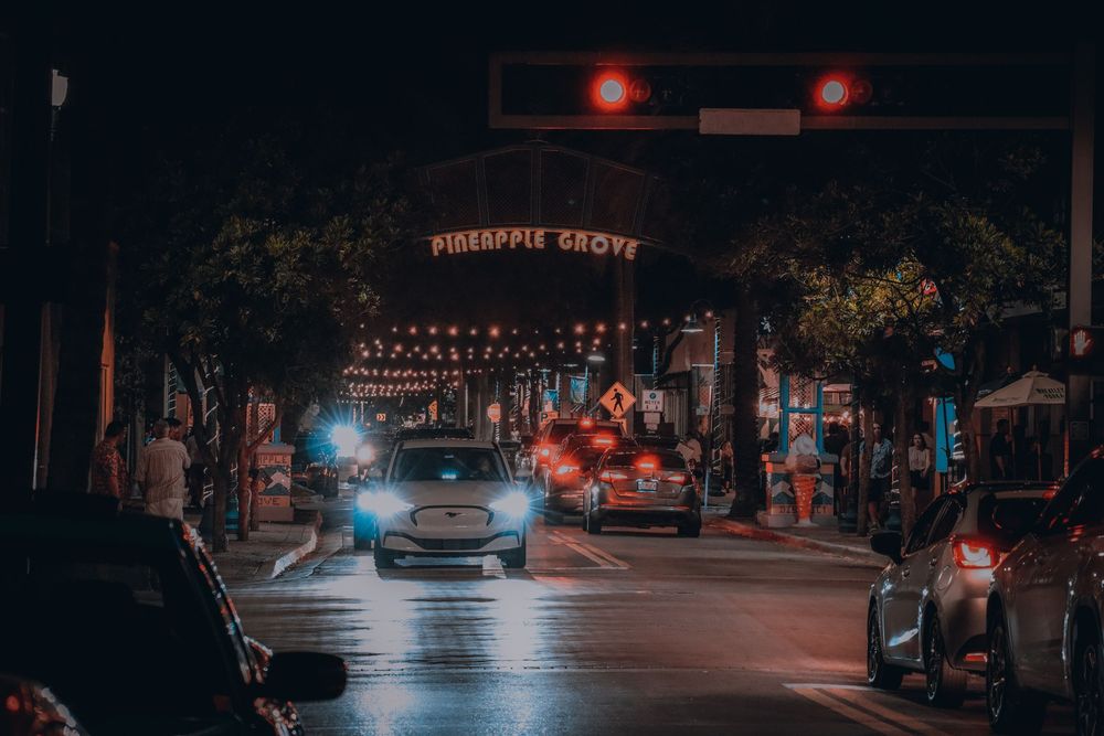 Dark urban street scene with glowing red lights and illuminated storefronts.