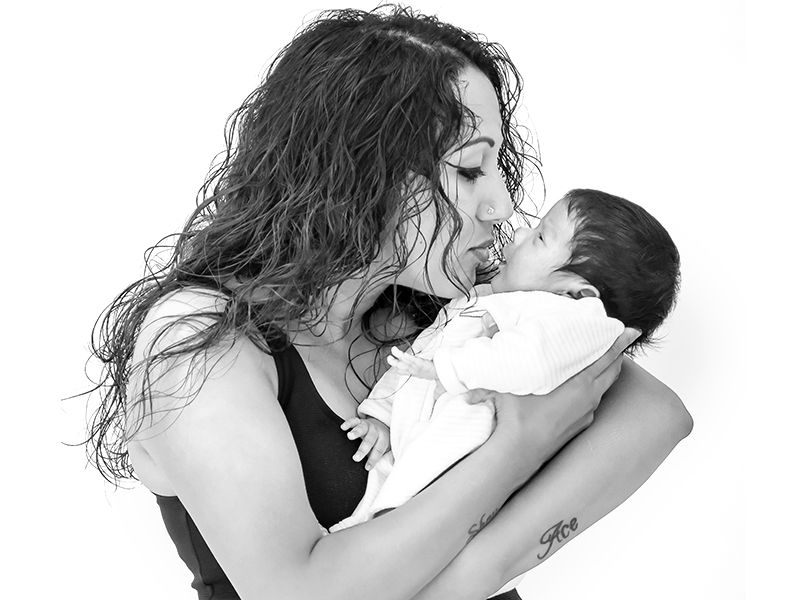 A mother lovingly holds her baby, showcasing a heartfelt moment in newborn photography by Abigail's Studio, Buckinghamshire.