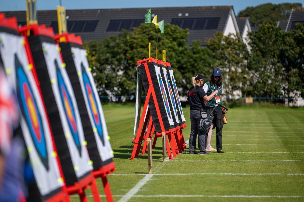 Colorful red and blue banners line a green grassy field during an outdoor event on a sunny day.