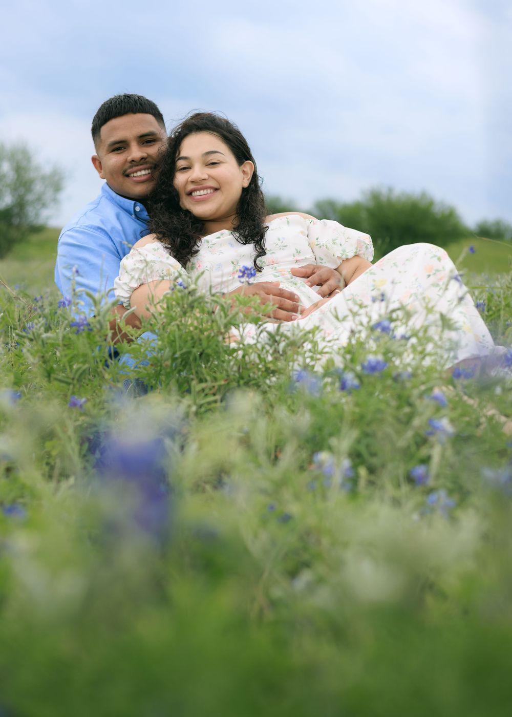Couple session on blue bonnet field snuggling together, while smiling.